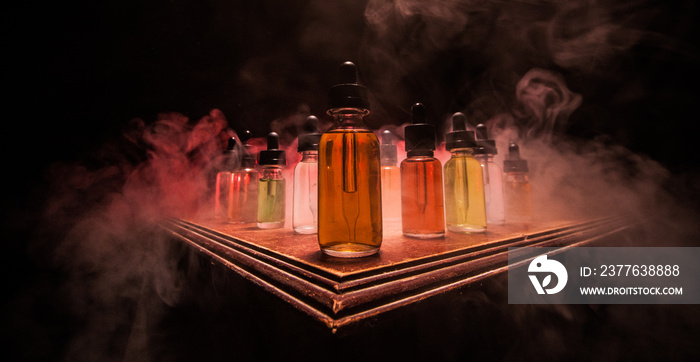 Smoke clouds and vape liquid bottles on dark background. Light effects. Useful as background or vape advertisement or vape background. Selective focus