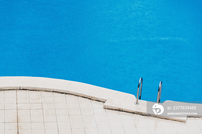 Summer storm, a fine rain falls on the blue water of a swimming pool in a hotel.