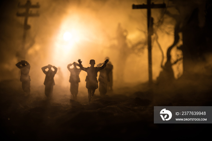 Battle scene. Military silhouettes fighting scene on war fog sky background. A German soldiers raised arms to surrender. Plastic toy soldiers with guns taking prisoner the enemy soldier. Artwork