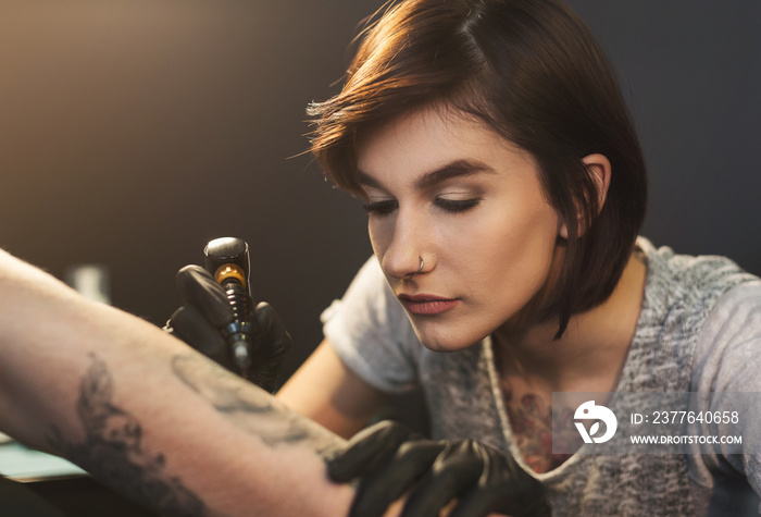 A professional tattooer artist doing picture on man hand