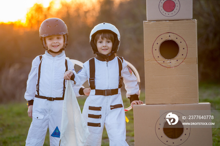 Two adorable children, playing in park on sunset, dressed like astronauts