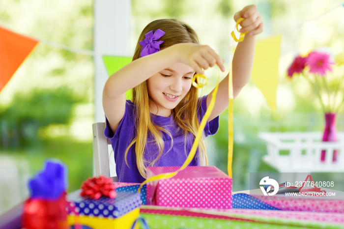 Cute preteen girl wrapping gifts in colorful wrapping paper.