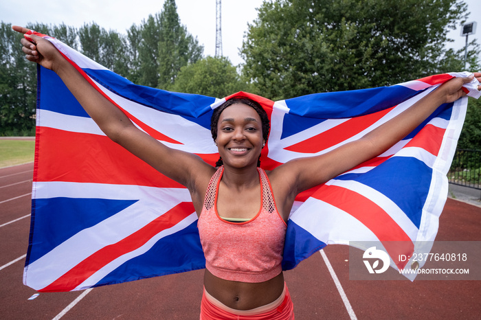 Portrait of smiling athletic�woman with British flag on running track