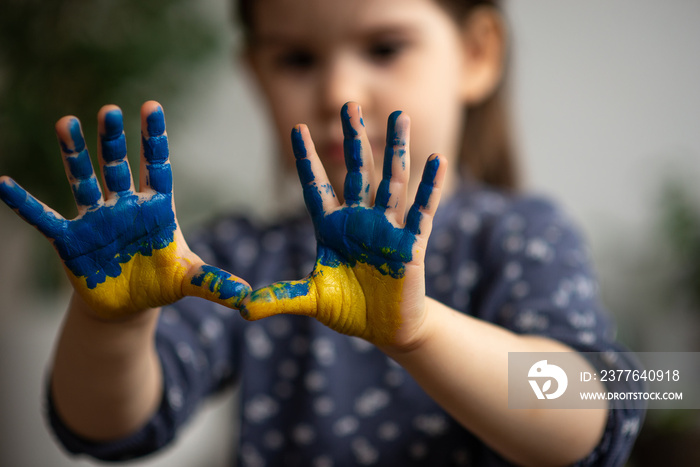 Little girl with hands in paints Ukrainian flag symbolic