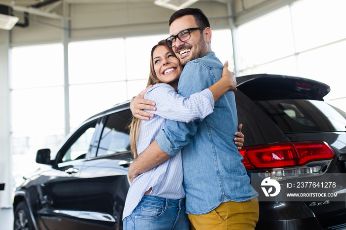 Beautiful young couple at car showroom choosing a new car to buy.