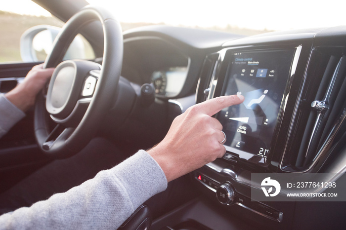 Man using navigation system while driving a car. Transport, destination, modern technology and people concept - male hand searching for route using navigation system on car dashboard screen.