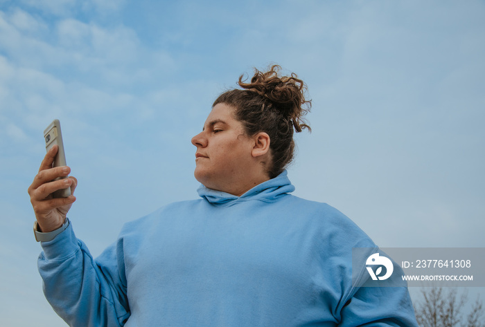 plus size woman wearing blue hoodie against a sky