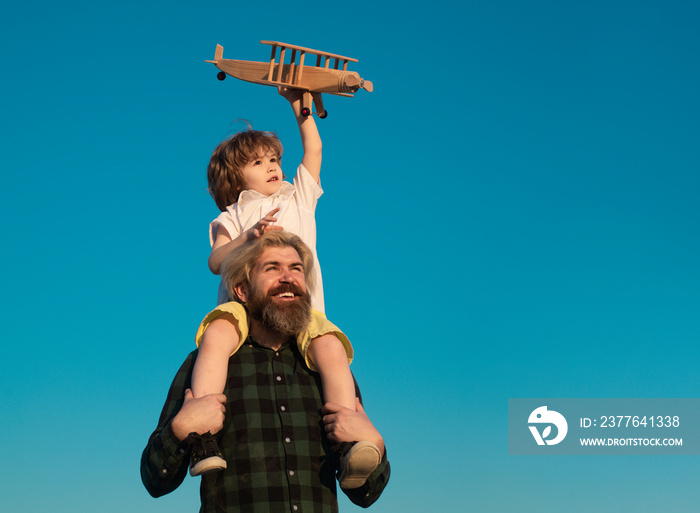 Child sits on the shoulders of his father. Kid playing imagination dream flying airplane, children’s day concept. Father and son. Parent with child boy.