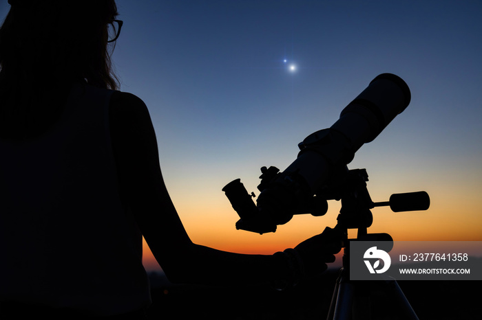 Woman looking at night sky with amateur astronomical telescope.