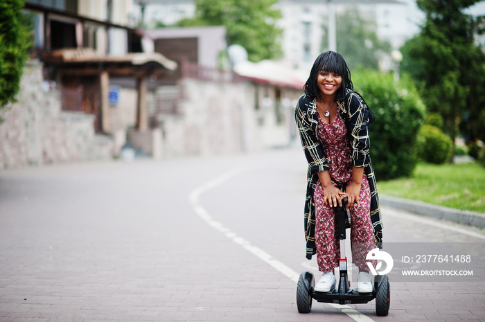 Beautiful african american woman using segway or hoverboard. Black girl on dual wheel self balancing electrical scooter.