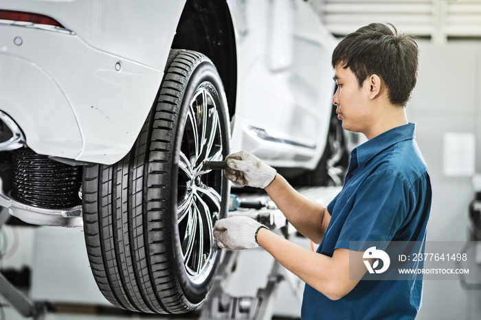 Asian mechanic checking and repairing the car wheels in maintainance service center which is a part of showroom, technician or engineer professional work for customer, car repair and maintain concept