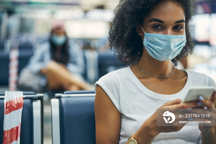 Happy smiling young woman in protective mask looking at the camera