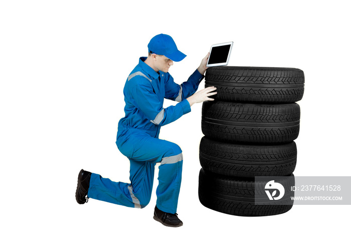 Caucasian mechanic checks tire with a tablet