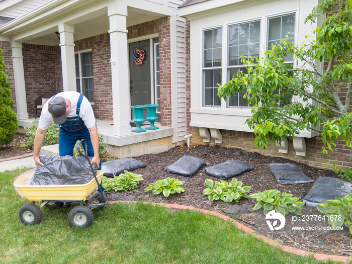 Man unloading bags of mulch into a flowerbed