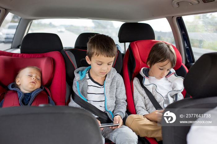 Three children, boys, siblings, traveling in car seats