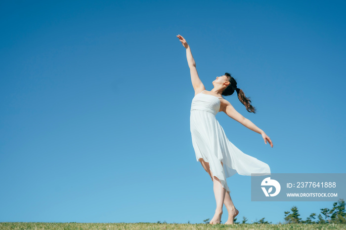 空と白いワンピースの踊る女性（深呼吸・全身）