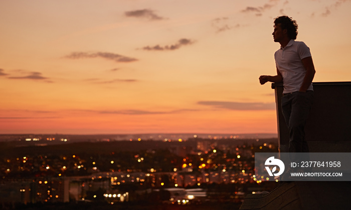 Man enjoying sunset from rooftop of city building