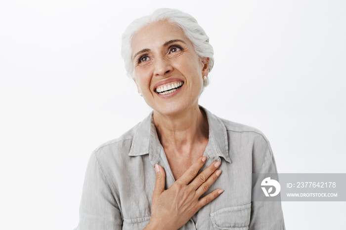 Waist-up shot of happy and delighted grateful charming old lady with white hair holding palm on chest in thankful gesture gazing dreamy and pleased at upper left corner cheerful have awesome family