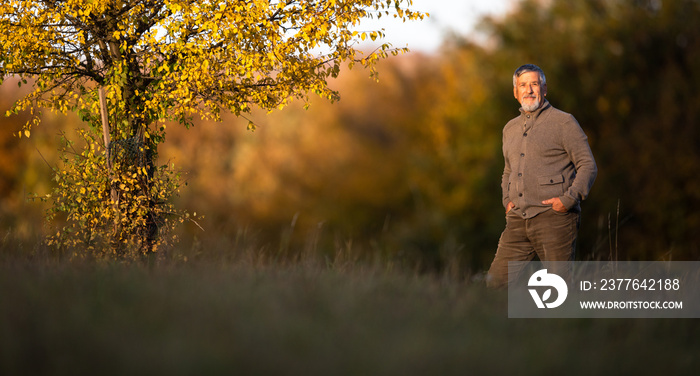 Portrait of handsome senior man in the autumn outdoors. Active senioor enjoying his retirement in the  nature