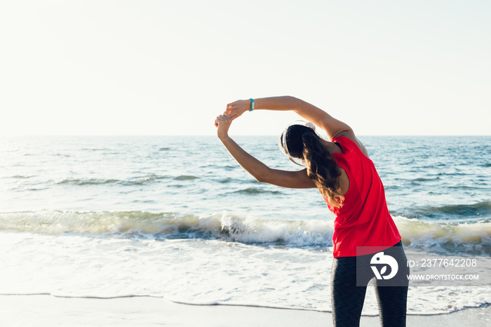 Sportswoman in a red t-shirt with headphones doing exercises on