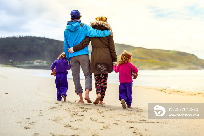 Happy young family is walking on sandy beach and ocean. 