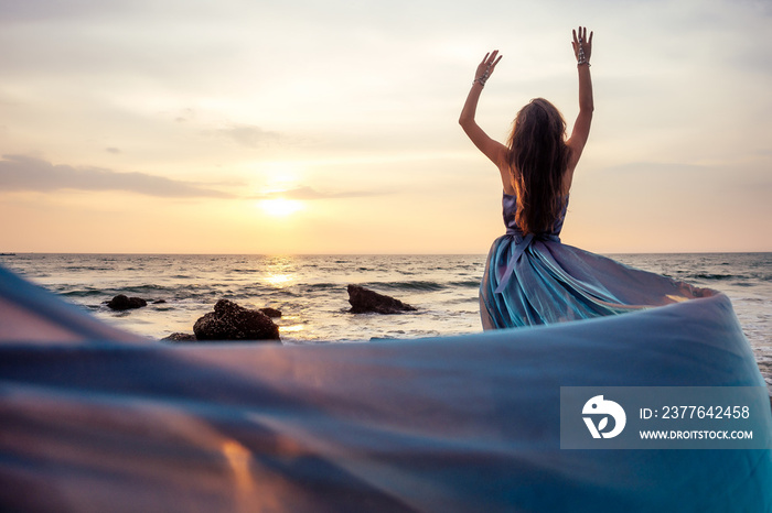 gorgeous style brunette young woman in blue chameleon dress long train standing on a rock near the sea, sand tropical on a rock.beautiful mermaid lonely melancholy waiting freedom and freelancing