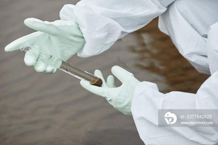 Close up of unrecognizable scientist wearing hazmat suit collecting water probes, focus on gloved hands holding test tube