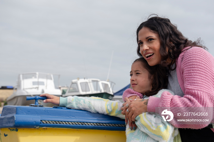 Portrait of smiling mother embracing daughter while standing by nautical vessel