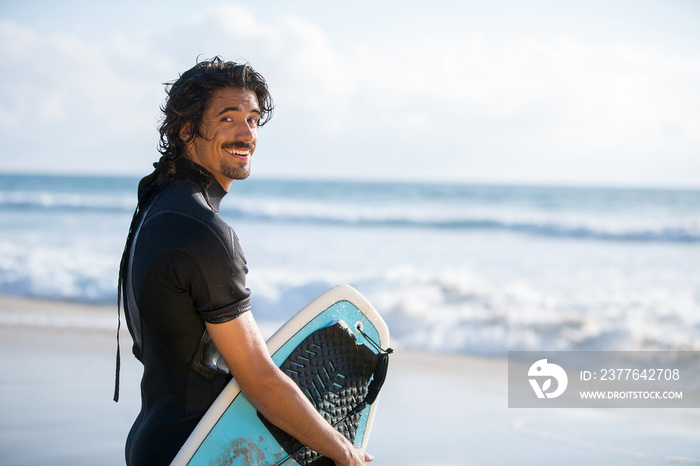 Portrait of handsome surfer with board