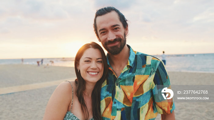 Young couple standing on the beach at sunrise