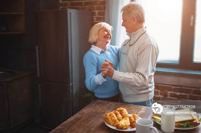 This couple has a splendid time dancing in the kitchen and remembering old times. They are looking to each other with joy and comfort.