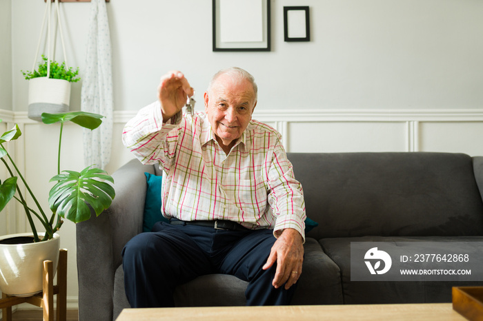 Happy old man looking cheerful about moving holding his apartment or home keys