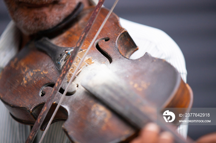 Close up partial photo of an old musician holding violin in his hand and playing the classical melody being outdoors.