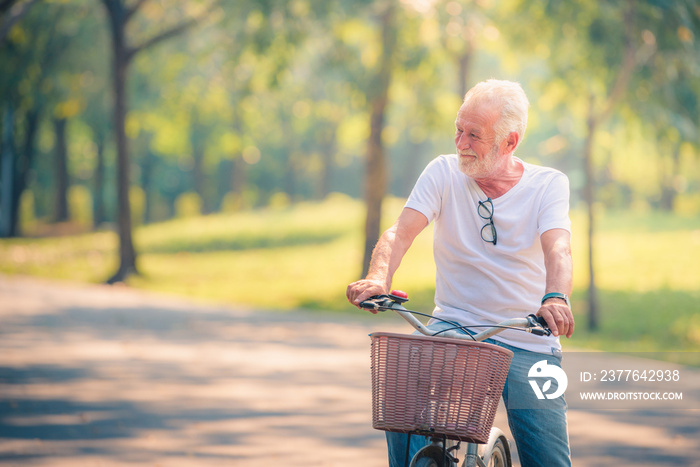 Old Man Riding on Bicycle in garden at sunset. Healthcare Concept. Relaxing in Park.