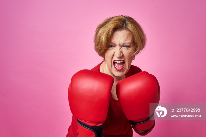 Woman aged in boxing gloves. The concept of the fight against old age.