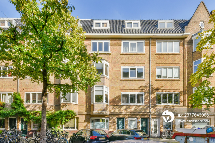 an apartment complex in the netherlands, with bikes parked on the street and cars parked along the curbed road