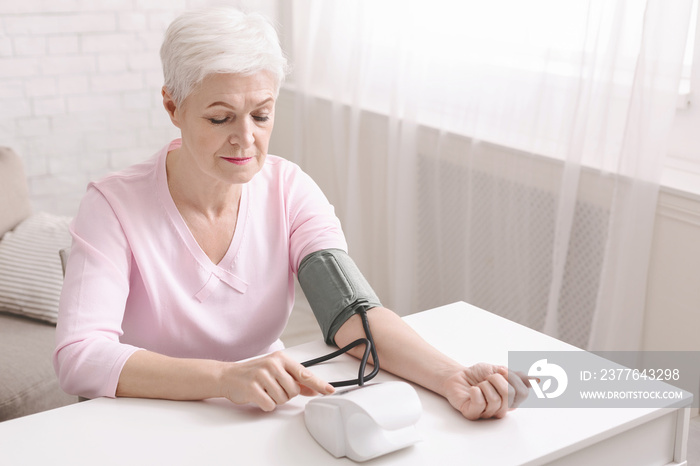 Senior lady with hypertension measuring blood pressure herself