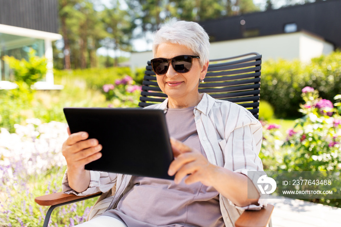 technology, old age and people concept - happy smiling senior woman in sunglasses with tablet pc computer resting at summer garden