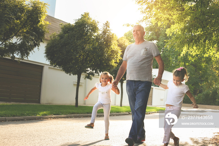 Children walking with their  grandfather holding hands.