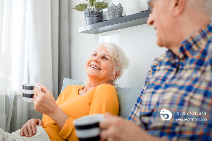 Senior couple at home spending time together drinking tea or coffee