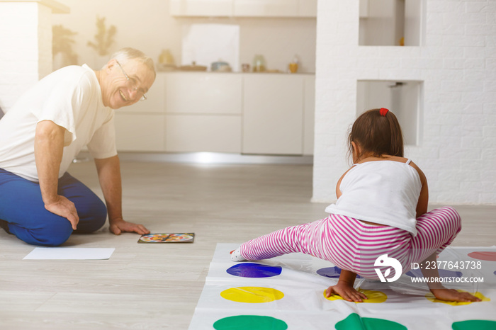 little girl and grandfather play twister at home