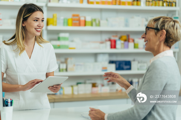 Male pharmacist selling medications at drugstore to a senior woman customer