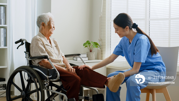 Young Asian woman nurse, caregiver assist a senior Asian woman to do physical therapy and exercise leg at home.