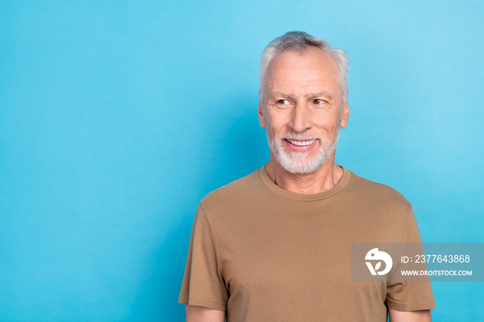 Portrait of confidant handsome pensioner man with gray hair beard dressed beige t-shirt look empty space isolated on blue color background