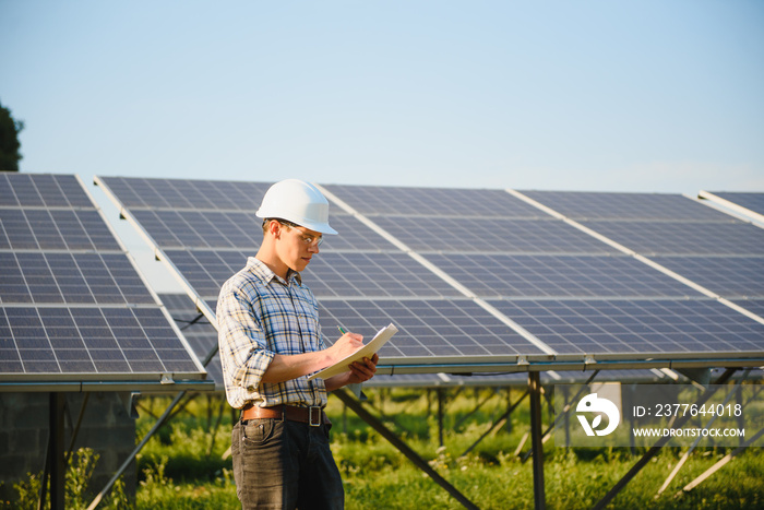 Solar power plant. Man standing near solar panels. Renewable energy.