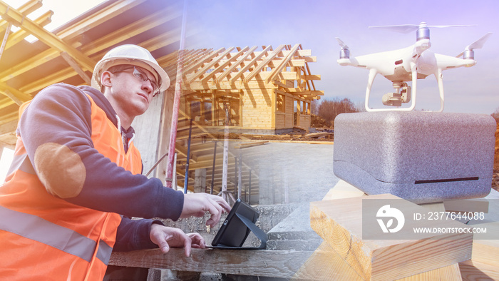 Monitoring the progress of construction using a quadrocopter. An engineer controls a drone to explore hard-to-reach fragments of a future home. Builder with a tablet and a quadcopter.