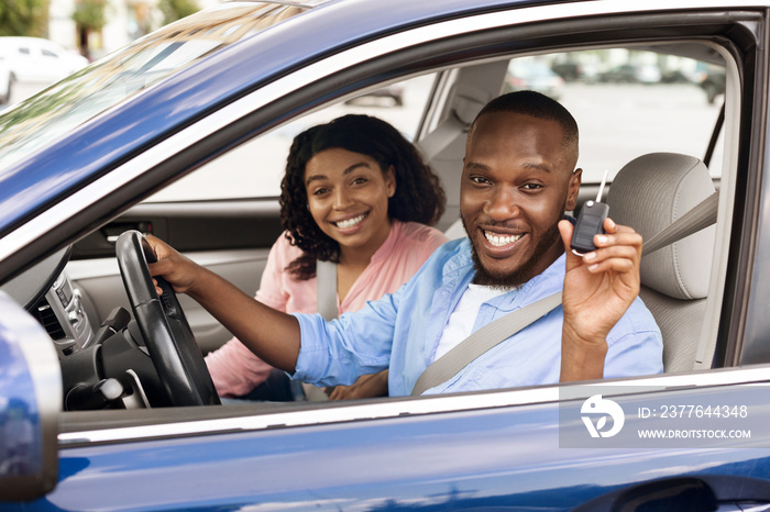 Happy black couple sitting in car showing keys