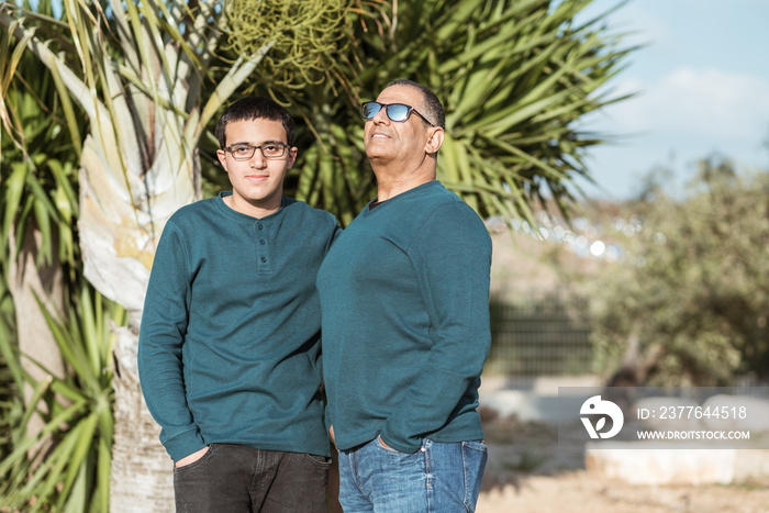 Teenager boy with senior father in park.