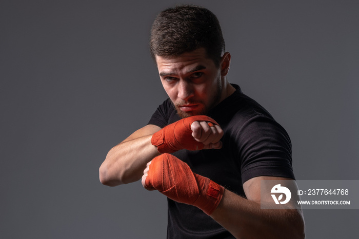 Focused young boxer with hand wraps working out defensive stance