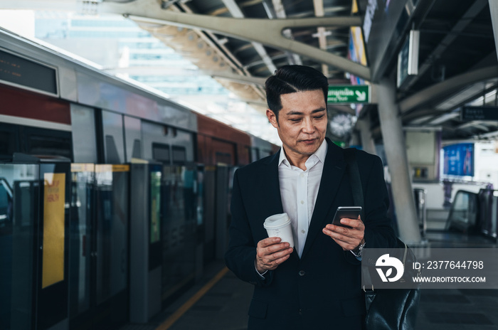 Serious business man using smart phone and waiting at train station